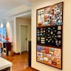 - A decorative corkboard display with photos, souvenirs, and artwork on a beige wall in a cozy living room.